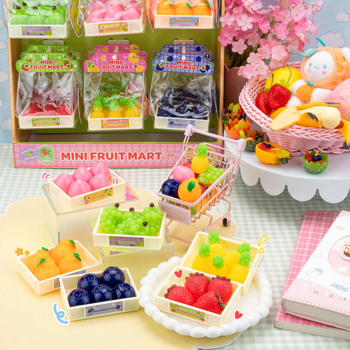 Miniature fruit mart set with colorful fruits and a shopping cart on a checkered tablecloth.