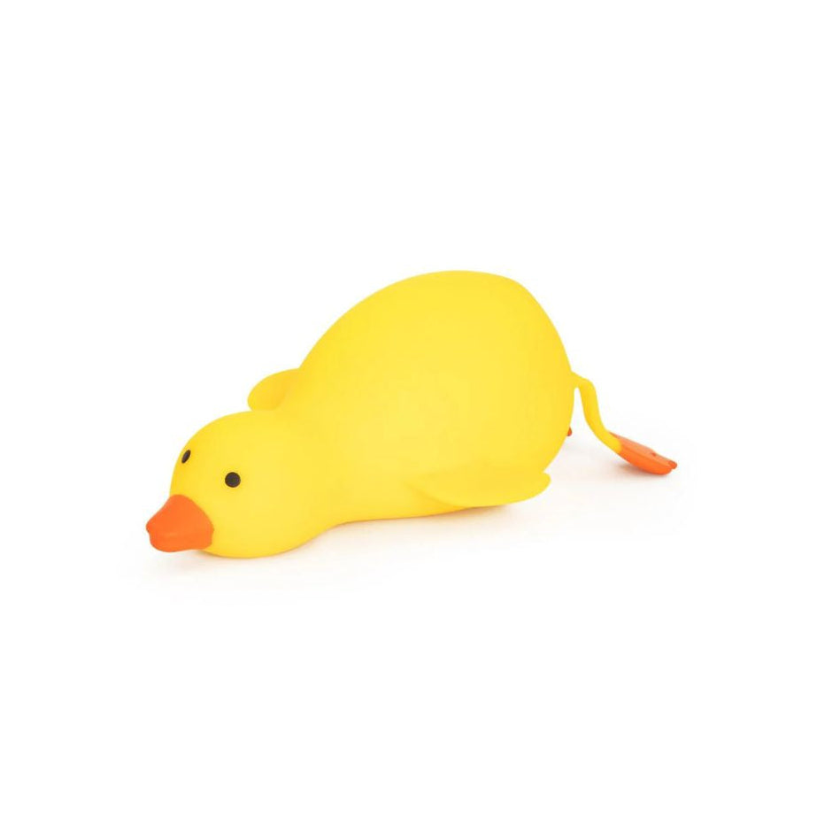 Side view of a large yellow duck‑shaped squishy toy lying flat, with an orange beak, small black eyes, and orange feet extending behind, shown on a white background.