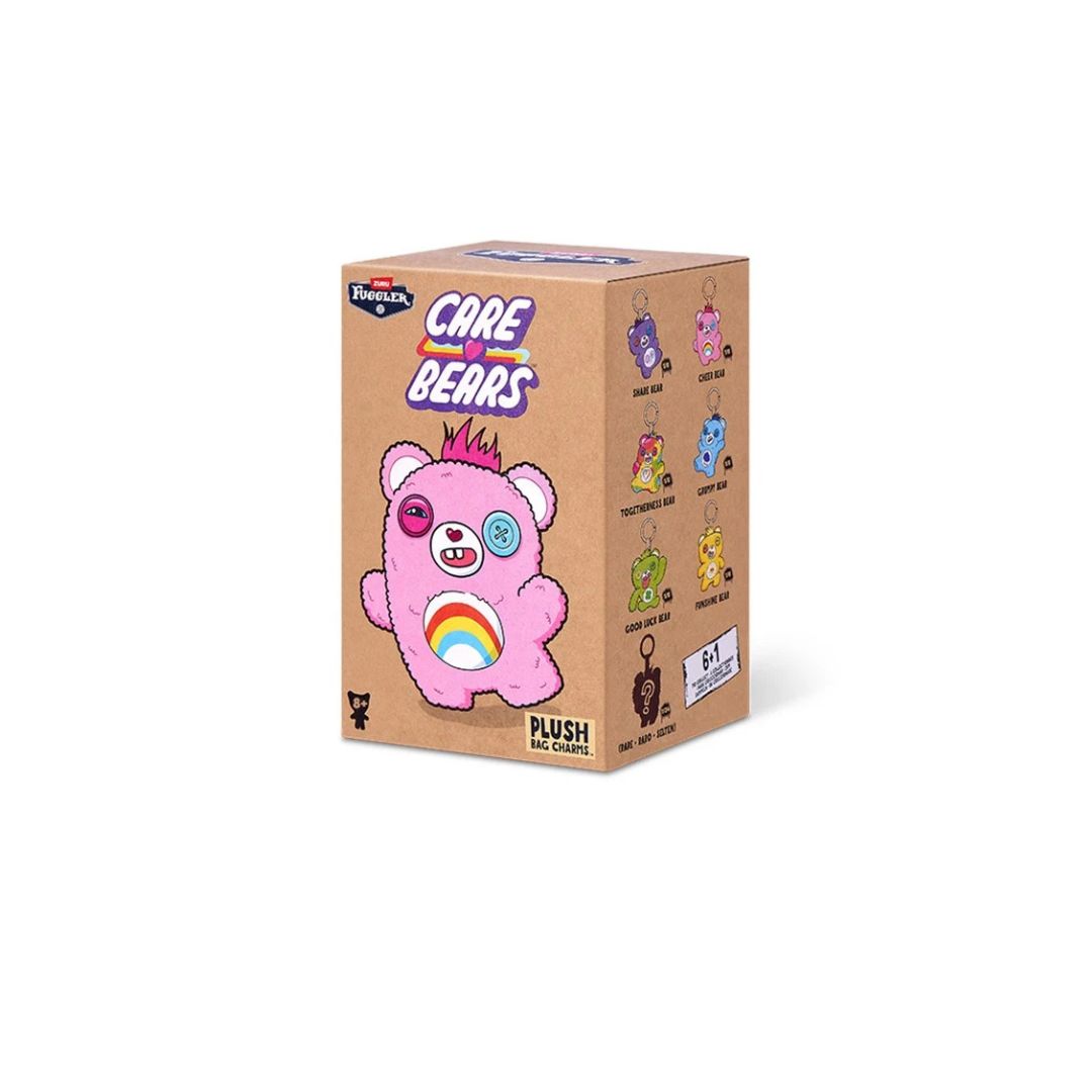 rectangular “Care Bears” blind‑box package for plush bag charms, featuring a pink teddy bear with a rainbow belly on the front and small illustrations of different bear characters shown on the side.