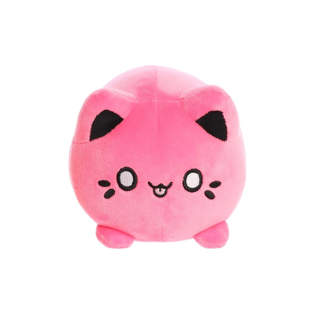 Front view of a small pink plush toy shaped like a round cat, with black ear tips, embroidered eyes, whisker markings, a small stitched mouth with tongue showing, and short stubby legs, displayed on a white background.