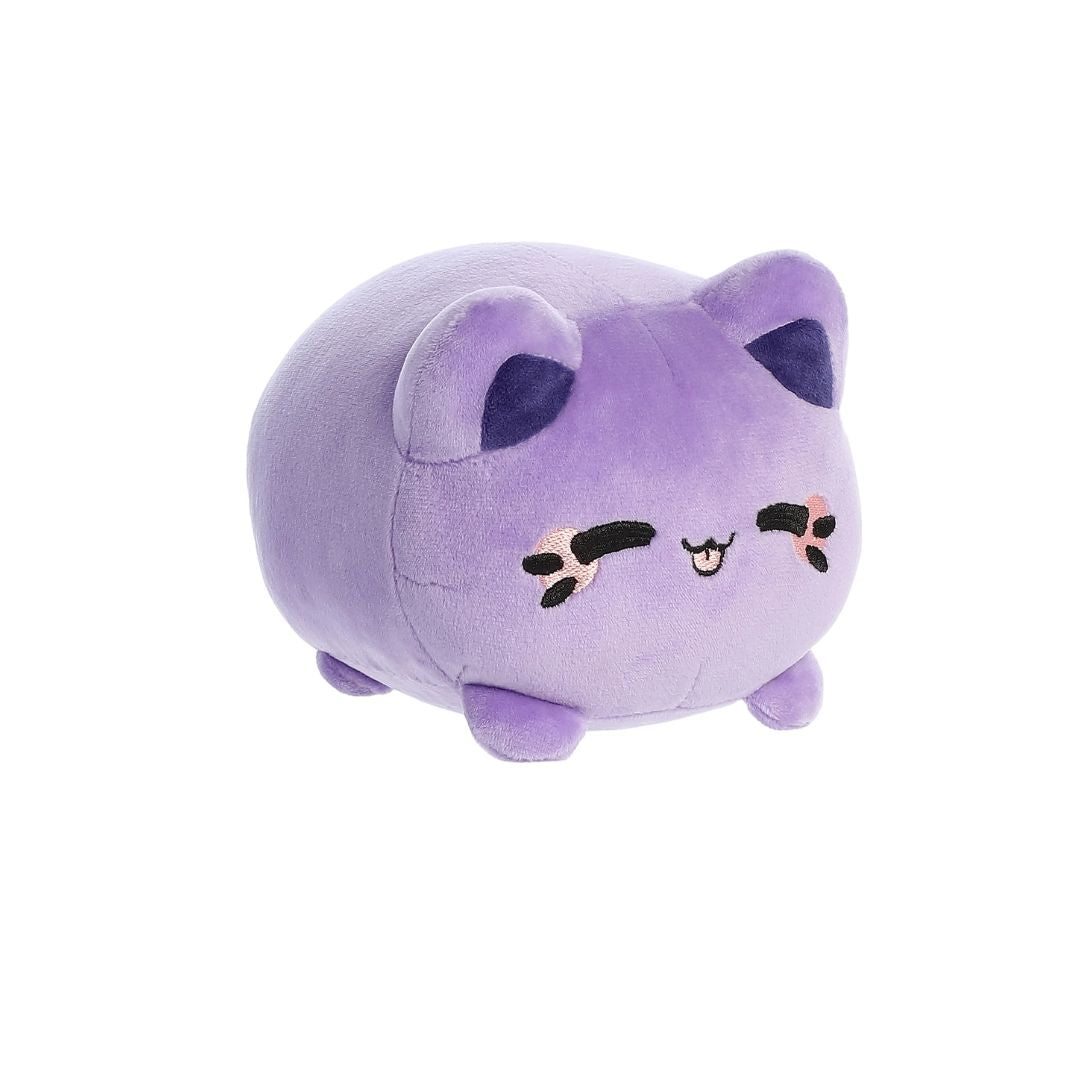 Angled front view of a small lavender‑purple plush toy shaped like a rounded cat, with darker purple inner ears, embroidered closed eyes, whisker markings with pink accents, a small stitched smiling mouth, and short stubby legs, shown on a white background.