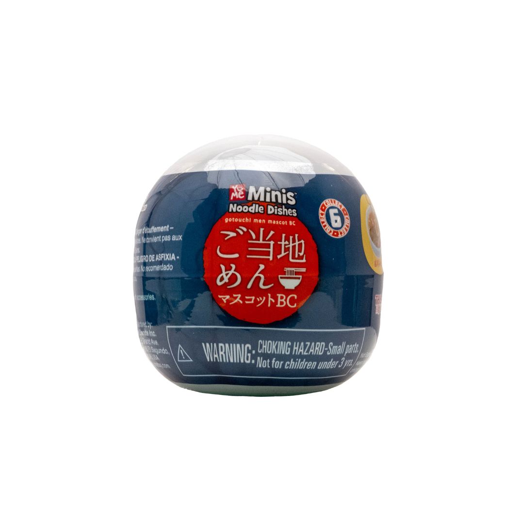 Dark blue capsule toy labeled 'Minis Noodle Dishes’ with Japanese text and a choking hazard warning, shown on a white background