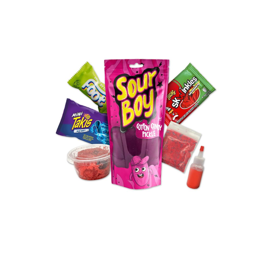 A pink “Sour Boy Cotton Candy Pickle” package surrounded by assorted snacks, including Takis, gummies, red candy powder, and a small bottle of red liquid, displayed on a white background