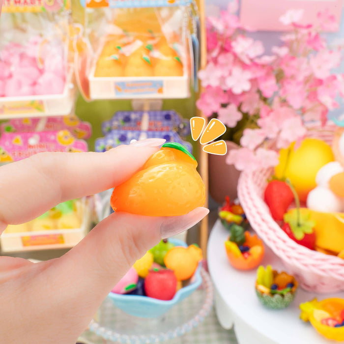 Hand holding a small orange fruit toy with a colorful background