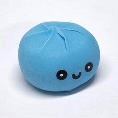 A light blue, round, dumpling-shaped edible candy with a cute black embroidered face, shown on a plain white background.