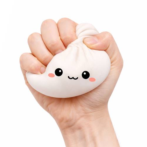 Hand holding a cute white dumpling squishy stress reliever with a face on a white background