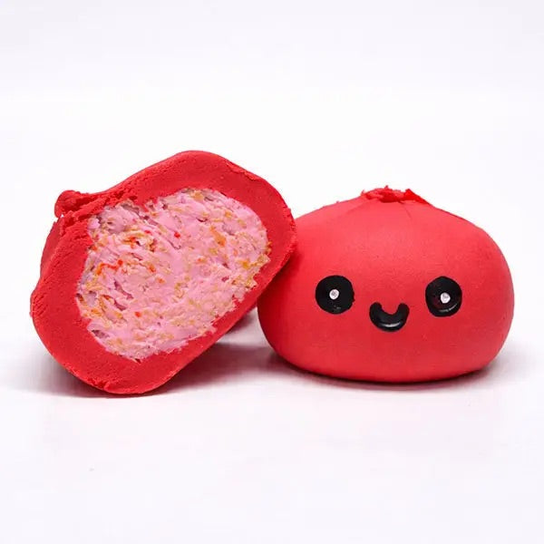 A red, round, chewy dumpling with cute black-and-white face and pink filling, photographed on a plain white background.