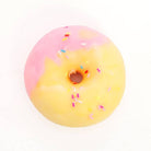 A novelty donut-shaped object with a pink and yellow gradient glaze and colorful sprinkles, photographed from above on a plain white background.