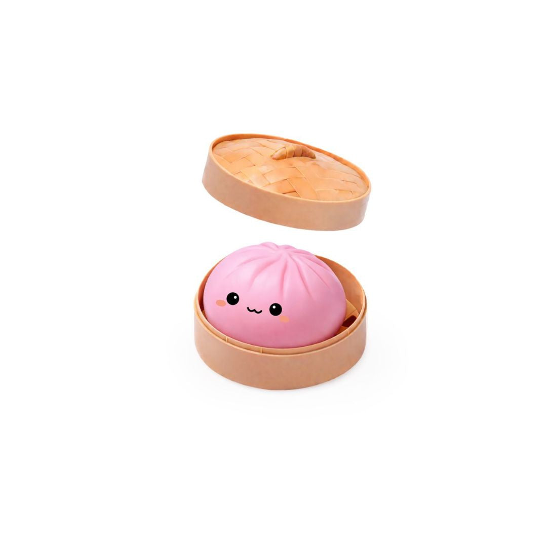 Open round tan container with the lid hovering above, holding a pink dumpling‑shaped squishy toy with a small smiling cartoon face, shown on a white background.