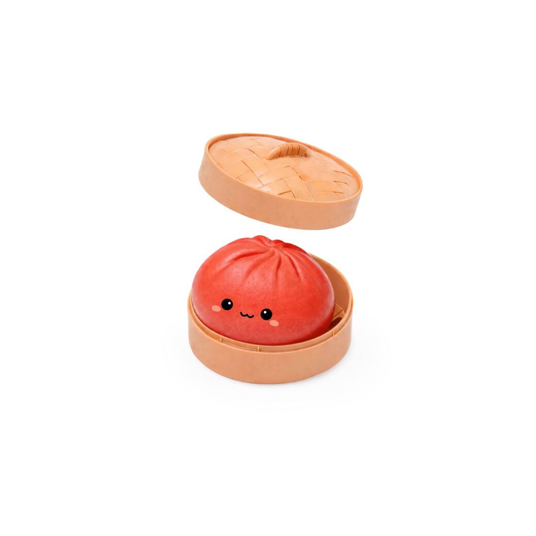 Open round tan container with the lid slightly raised, holding a red dumpling‑shaped squishy toy with a small smiling cartoon face, shown on a white background.