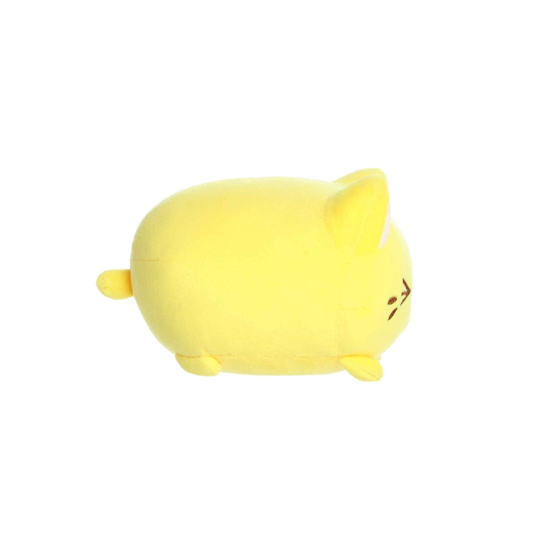 Side view of a small yellow plush toy shaped like a rounded cat, with short legs, a tiny tail, white inner ears, and minimal embroidered facial details, shown on a white background.