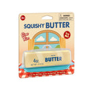 Packaged ‘Squishy Butter’ novelty toy shaped like a stick of butter inside a clear plastic case, displayed on a picnic‑style cardboard backing