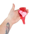 Hand squeezing a red and pink gel-like substance against a white background