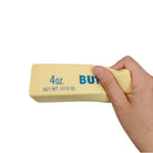 Hand holding a 4oz block of a squishy butter toy against a white background