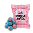 A pink and white striped bag of Bubble Gore Ultra Sour candies with a pile of blue and red sugar-coated candies in front, on a solid white background.
