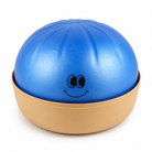 A blue squishy dumpling toy with a black cartoon face, resting inside a beige plastic base on a white background.