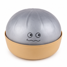 A novelty squishy dumpling toy shaped, featuring a metallic silver top half with a simple black face and a beige bottom half in a bowl-like base, shown on a white background.