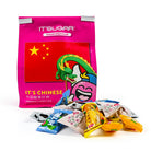 A bright pink bag of IT'SUGAR Chinese candy mix with a red Chinese flag graphic and a cartoon dragon, with several individually wrapped candies spilled in front on a white background.