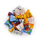 A pile of assorted Chinese snacks and candies in colorful individually wrapped packages, including yellow, blue, red, white, and black wrappers, photographed on a plain white background.