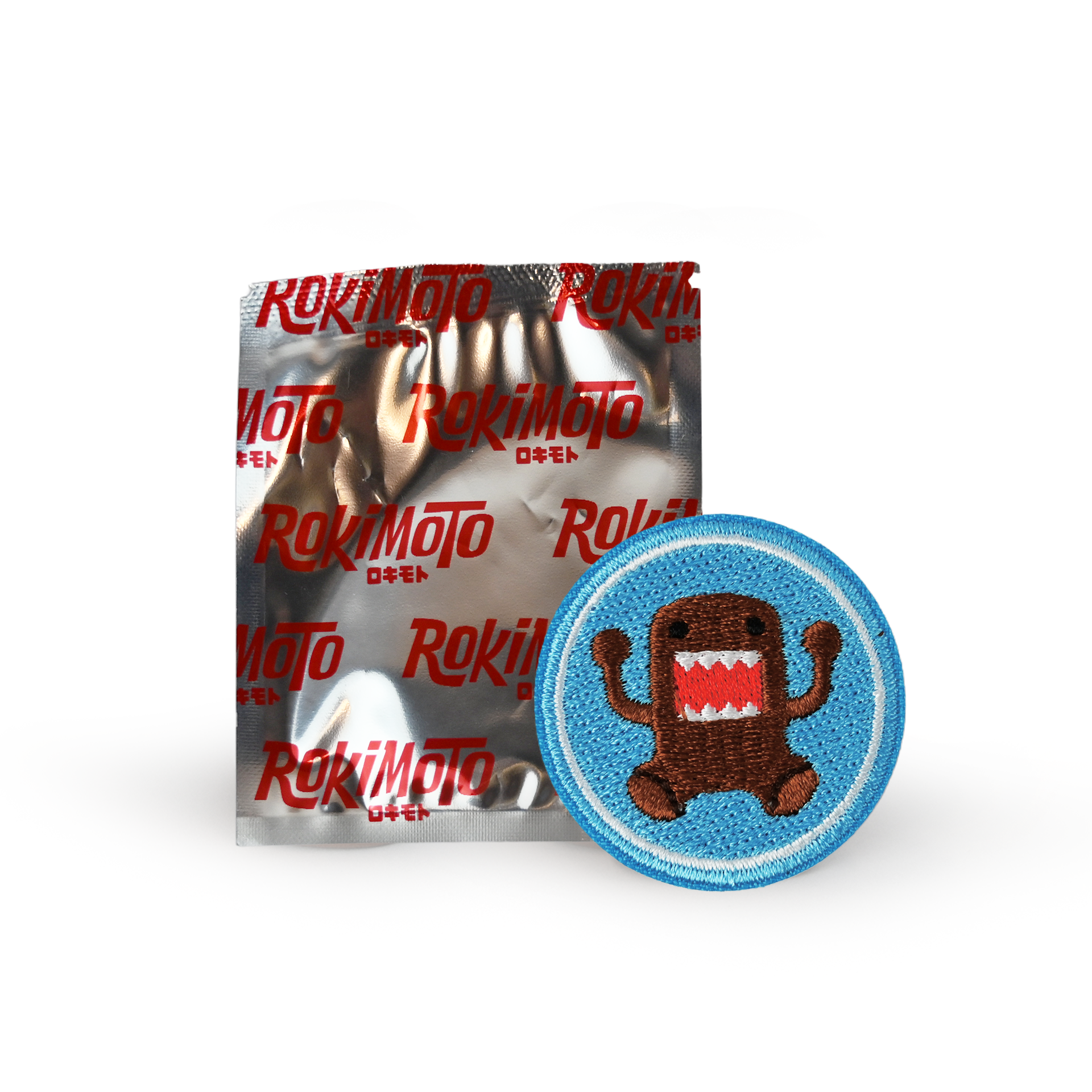 Silver pouch with red text "Rokimoto" next to a blue patch with an image of Domo