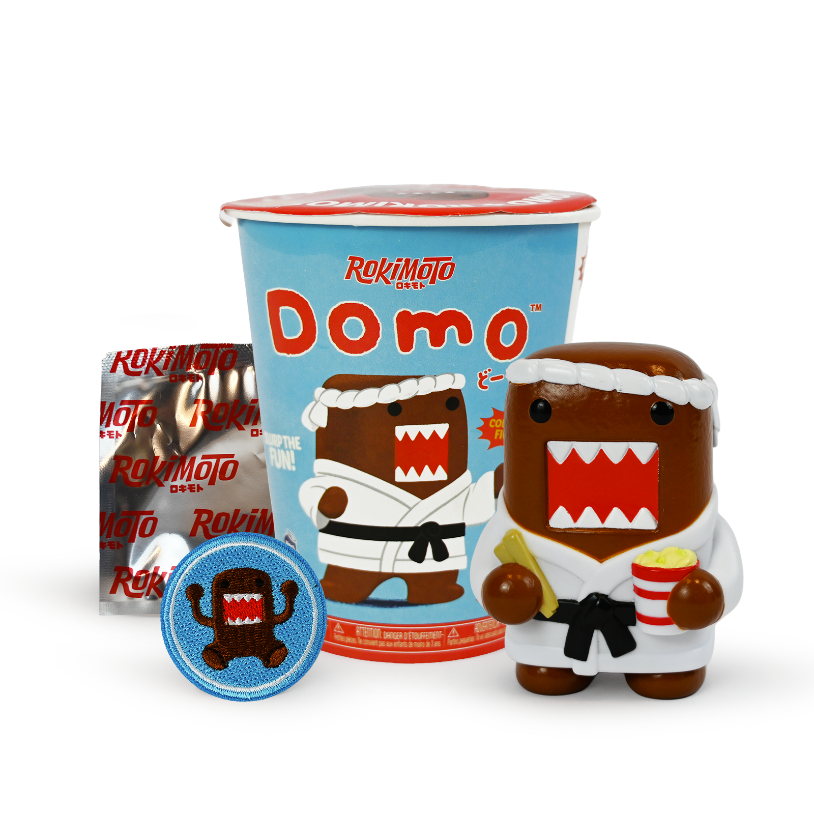 Light blue ramen cup with image of Domo in Karate uniform in the middle, to the left is silver pouch with red text "Rokimoto". Below is blue patch with image of domo. To the right is a figure of Domo in a Karate uniform