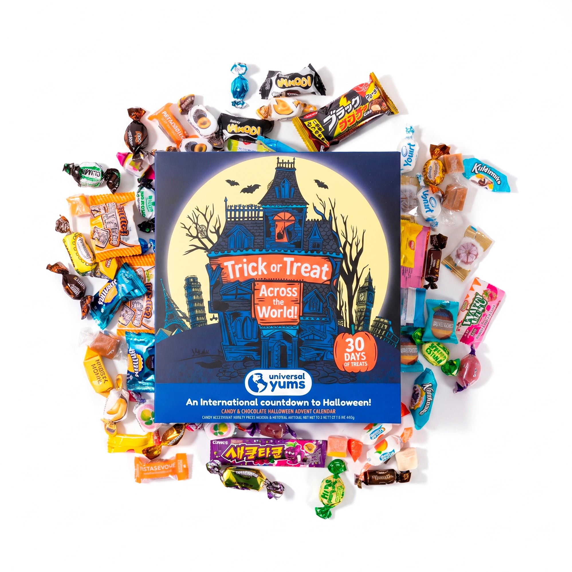 A boxed candy countdown product labeled 'Trick or Treat Across the World!' surrounded by assorted wrapped candies on a white background. The box is dark blue with a haunted-house illustration and a yellow moon, and the brand 'International Yums' is visible on the front.