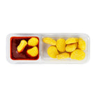 A clear plastic two-compartment tray containing yellow sugar-coated candy pieces, with one compartment holding three pieces dipped in chamoy sauce, shown on a white background.