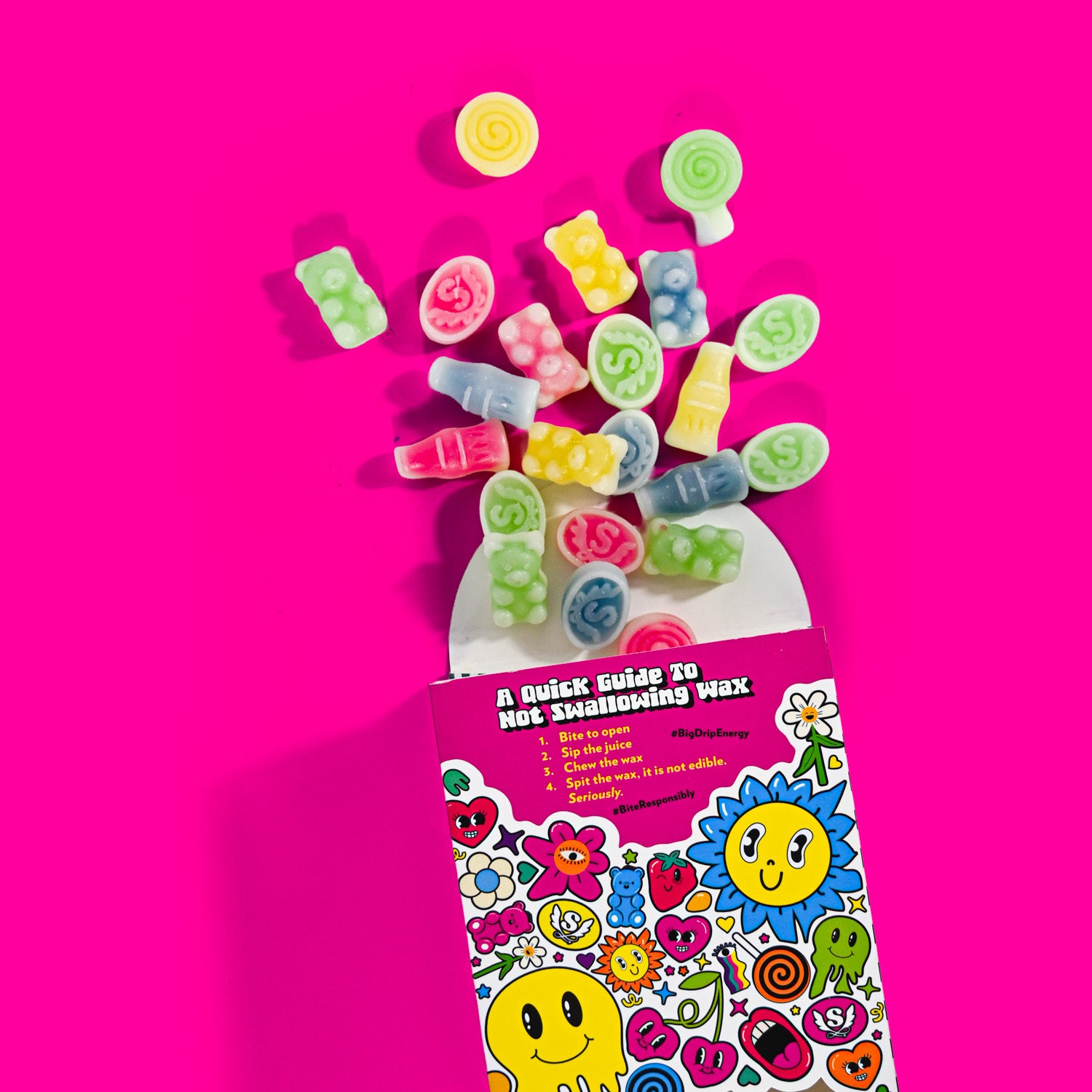 Colorful gummy candy shaped like letters spilling out of a box with a pink background