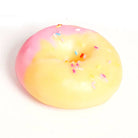 A novelty squishy toy shaped like a donut, featuring a two-tone pink and pale yellow glaze with colorful sprinkles, on a plain white background.