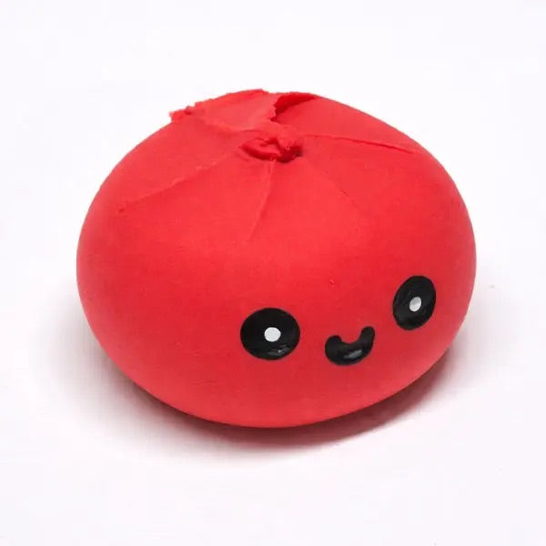 A red, round, chewy dumpling with cute black-and-white face, photographed on a plain white background.