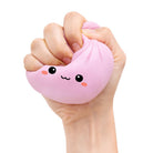 Hand holding a pink squishy dumpling toy with a face design on a white background