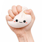 Hand holding a cute white dumpling squishy stress reliever with a face on a white background